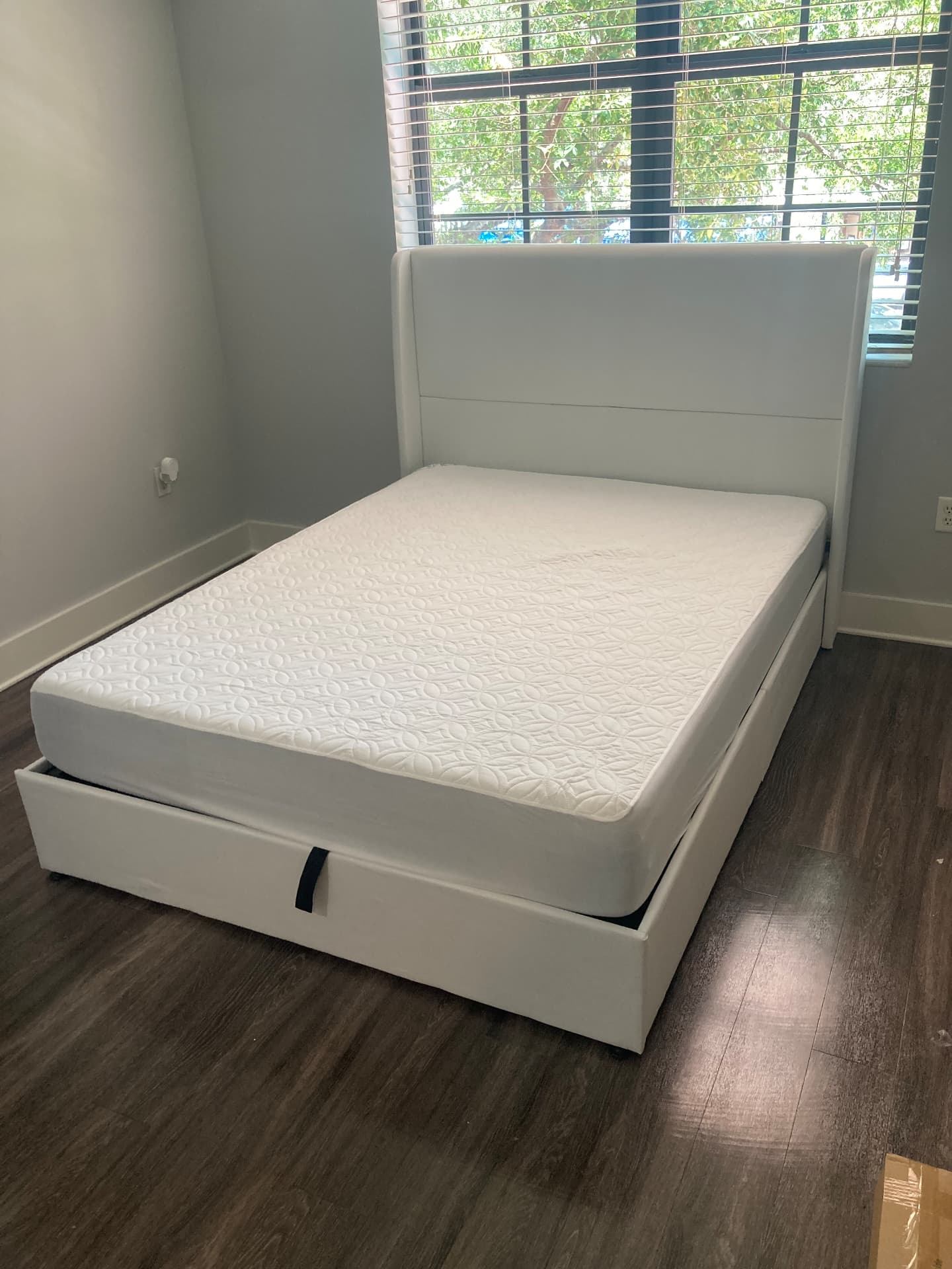 White lift-up storage bed with mattress assembled in a Boca Raton bedroom