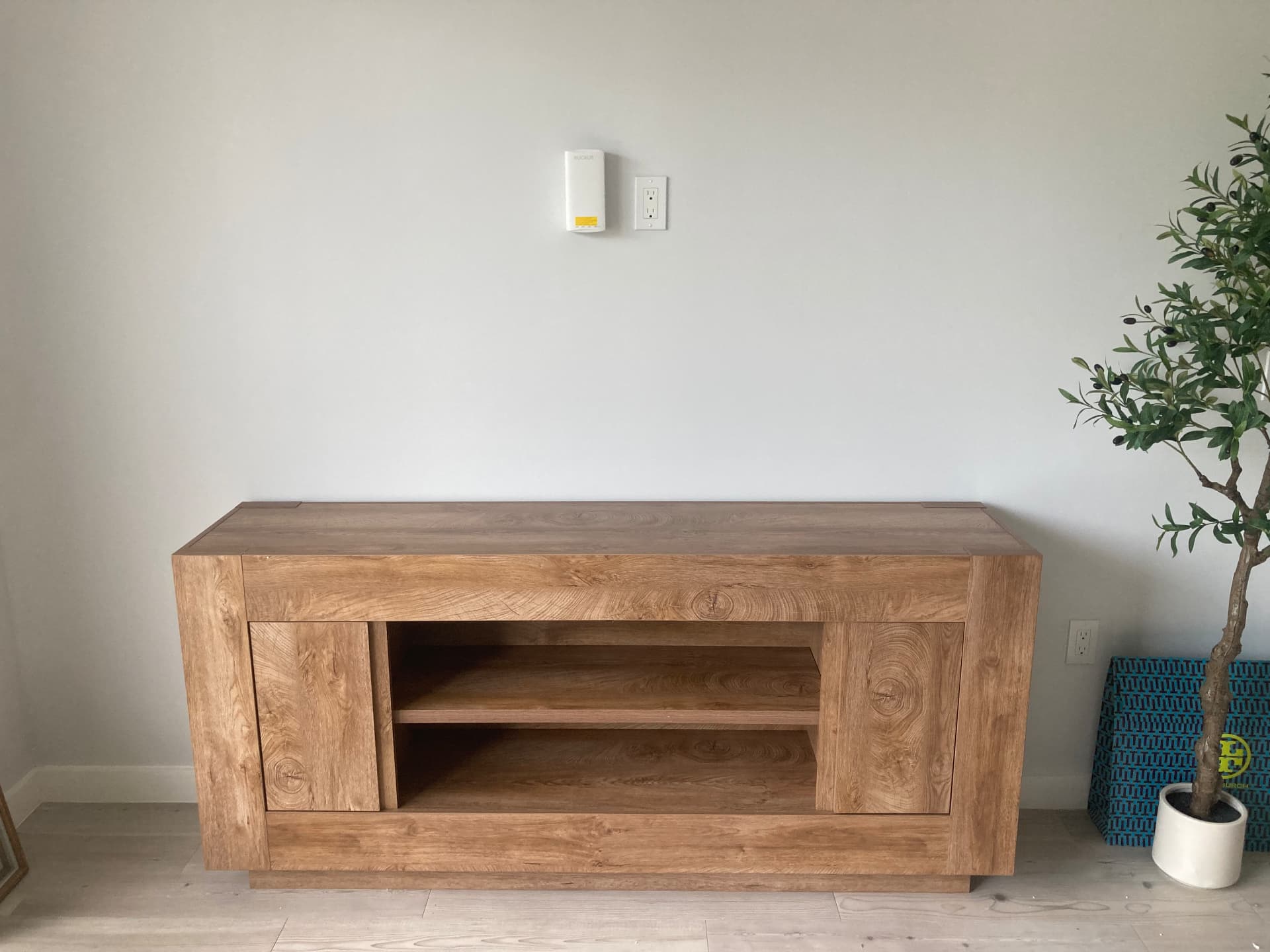 Assembled light oak media console TV stand with open shelving in a West Palm Beach living room