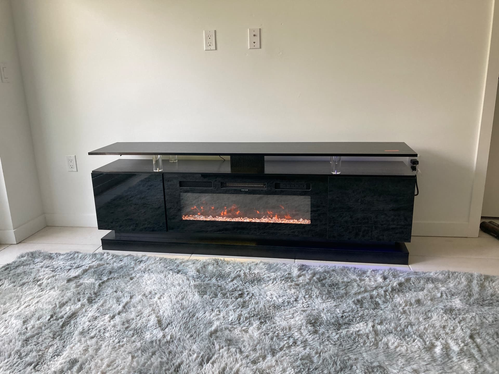 Black high gloss electric fireplace TV stand assembled with LED lighting in Boynton Beach