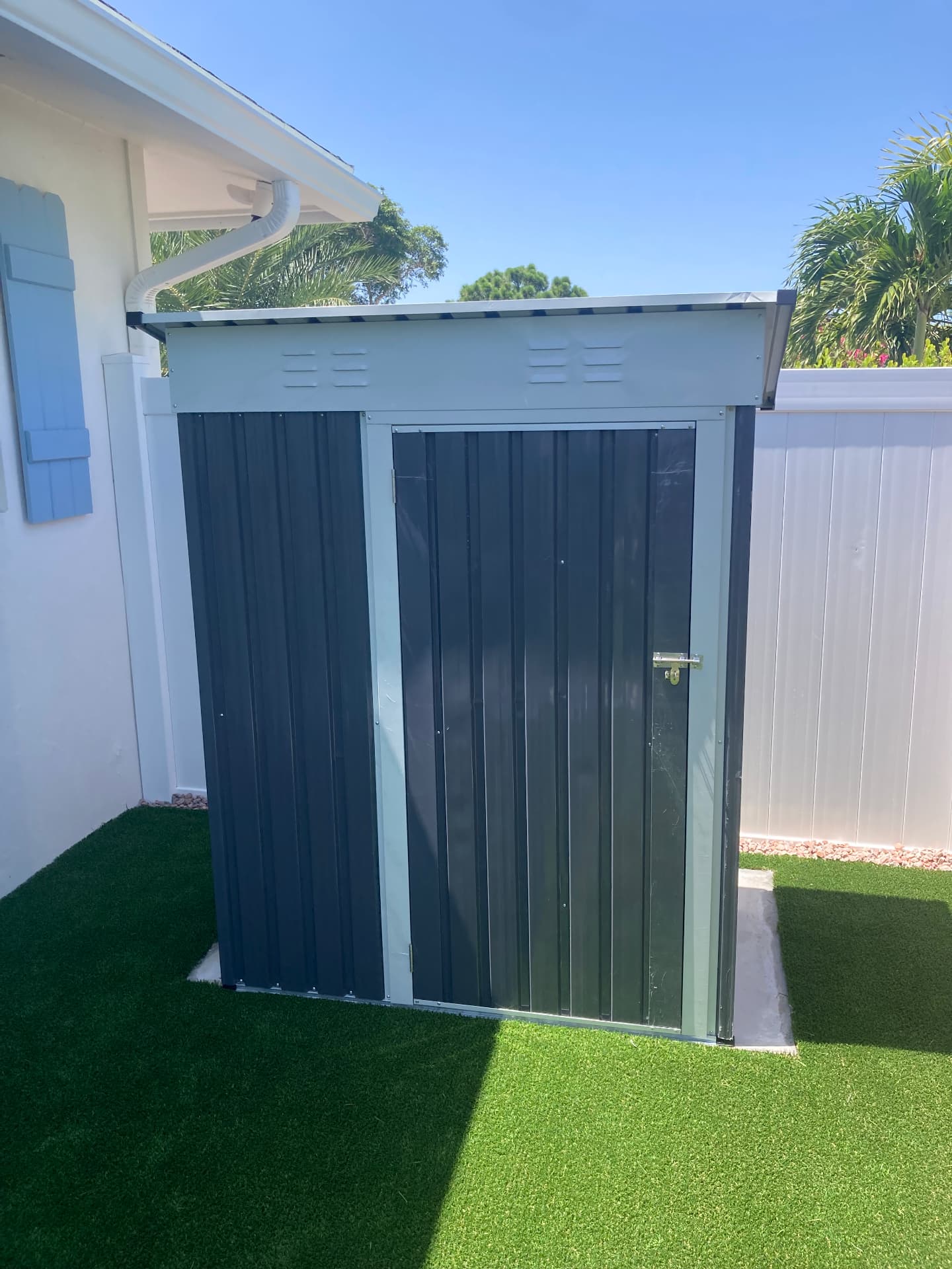 Grey metal outdoor storage shed built and installed in a Lake Worth Beach backyard