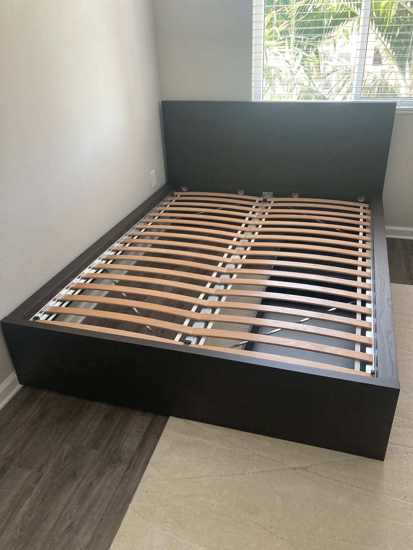 Dark wood platform bed frame with slatted base assembled in a Delray Beach bedroom